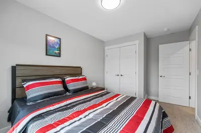 a bedroom with a large bed with red and gray pillows at Brand New Modern Home - 5 Beds - Office - Garage - Luxury Living - Sleeps 9 in Calgary