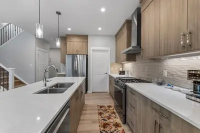 a kitchen with white counter tops and wooden cabinets at Brand New Modern Home - 5 Beds - Office - Garage - Luxury Living - Sleeps 9 in Calgary