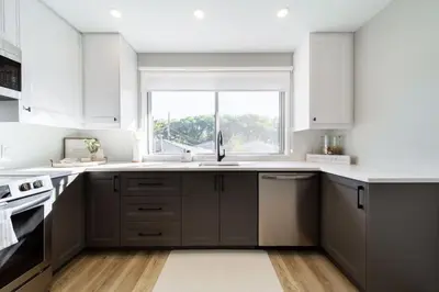 a kitchen with white cabinets and a sink and a window at Newly Renovated, Bright & Cozy 3 bdrm Home - 6min from Rogers Arena in Edmonton