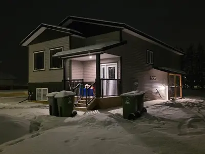 a house with two trash cans in the snow at night at Whitehorse Guest Stay in Whitehorse