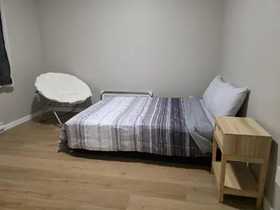 a bedroom with a bed with a chair and a table at Whitehorse Guest Stay in Whitehorse