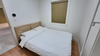 a small bedroom with a white bed and a window at Entire ground floor 2 Baths 3 Beds Full Privacy in Vancouver