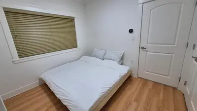 a small bedroom with a bed and a window at Entire ground floor 2 Baths 3 Beds Full Privacy in Vancouver