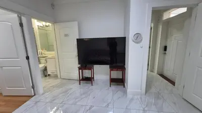 a living room with a television and a white wall at Entire ground floor 2 Baths 3 Beds Full Privacy in Vancouver