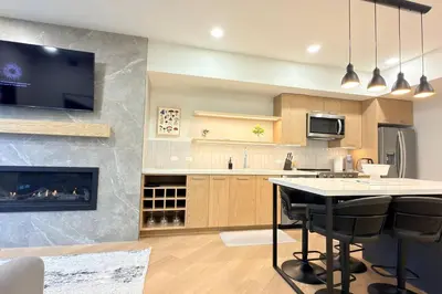 a kitchen with a fireplace and a table with bar stools at Canmore Peaks Retreat | Luxe 1BR w Pool & Gym in Canmore