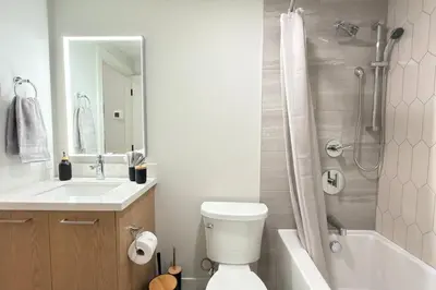a bathroom with a toilet and a sink and a shower at Canmore Peaks Retreat | Luxe 1BR w Pool & Gym in Canmore