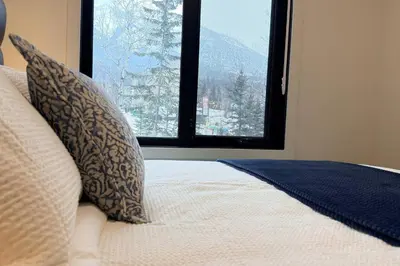 a bed with pillows and a window in a room at Canmore Peaks Retreat | Luxe 1BR w Pool & Gym in Canmore