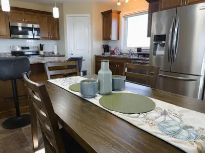 a kitchen with a wooden table and a refrigerator at Spacious 4BR with King Suite - Garage - Netflix in Lloydminster