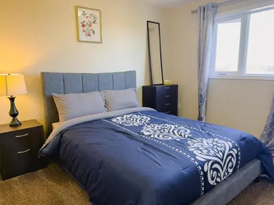 a bedroom with a bed with a blue comforter and a window at Spacious 4BR with King Suite - Garage - Netflix in Lloydminster