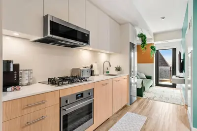 a kitchen with a stove top oven next to a living room at Incredible DT Views| King bed| Rest and Unwind in Calgary