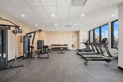 a gym with a row of treadmills and machines at Incredible DT Views| King bed| Rest and Unwind in Calgary