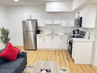 a kitchen with white cabinets and a stainless steel refrigerator at Stylish and Cozy 2-Bedroom Guest Suite in West Edmonton in Edmonton