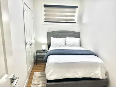 a small bedroom with a bed with white sheets and a window at Stylish and Cozy 2-Bedroom Guest Suite in West Edmonton in Edmonton
