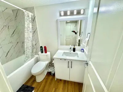 a white bathroom with a toilet and a sink at Stylish and Cozy 2-Bedroom Guest Suite in West Edmonton in Edmonton