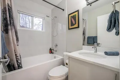 a white bathroom with a toilet and a sink at Renovated 3BE, 2BA close to UoC, downtown, SAIT in Calgary