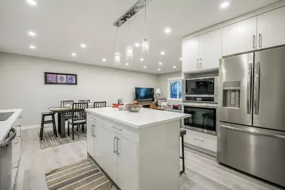 a kitchen with stainless steel appliances and a dining room at Renovated 3BE, 2BA close to UoC, downtown, SAIT in Calgary