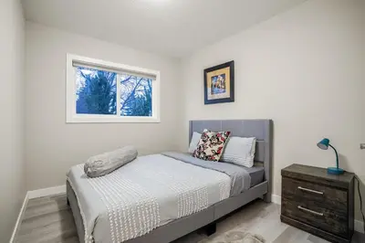 a small bedroom with a bed and a window at Renovated 3BE, 2BA close to UoC, downtown, SAIT in Calgary