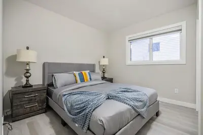 a white bedroom with a bed and a window at Renovated 3BE, 2BA close to UoC, downtown, SAIT in Calgary
