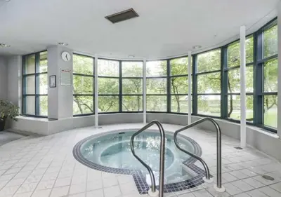 a swimming pool in a building with windows at Extra Spacious with a King Bed Sauna Pool & Jacuzzi in Vancouver
