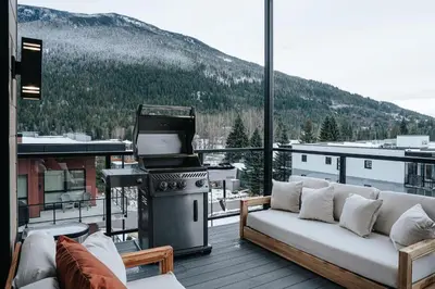 a living room with a stove and a couch on a balcony at Cloudscape Penthouse by Revelstoke Vacations in Revelstoke