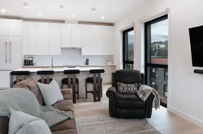 a living room with a couch and a kitchen at Cloudscape Penthouse by Revelstoke Vacations in Revelstoke
