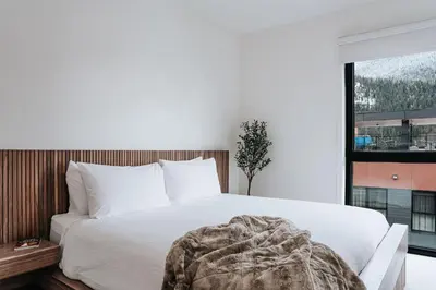 a bedroom with a white bed with a large window at Cloudscape Penthouse by Revelstoke Vacations in Revelstoke