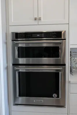 two ovens in a kitchen with white cabinets at Scenic Cochrane Family Home in Cochrane