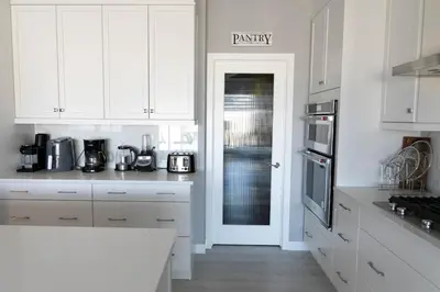 a kitchen with white cabinets and a pantry door at Scenic Cochrane Family Home in Cochrane