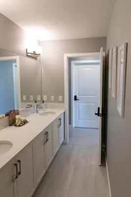 a bathroom with two sinks and a door with a mirror at Scenic Cochrane Family Home in Cochrane