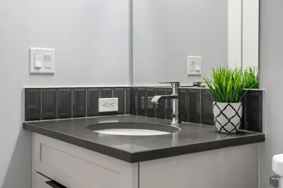 a bathroom sink with a black counter top at Modern 4BR Retreat 3 Baths Near to Banff&Airport in Calgary