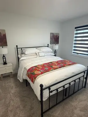 a bedroom with a large bed with a blanket on it at Slice of Heaven! 3 Bdrm Duplex 10 minutes drive to Spruce Meadows, with easy access to Stampede and Banff, CENTRAL AC available Mid Spring 2026! in Calgary