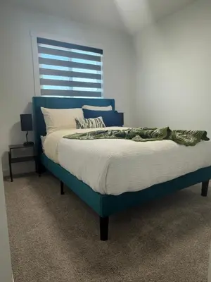 a bed in a bedroom with a blue headboard at Slice of Heaven! 3 Bdrm Duplex 10 minutes drive to Spruce Meadows, with easy access to Stampede and Banff, CENTRAL AC available Mid Spring 2026! in Calgary