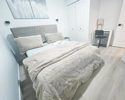 a bedroom with a large bed with a gray comforter at Ebenz Apartment in Calgary