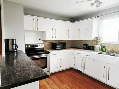 a kitchen with white cabinets and black appliances at House in Edmonton