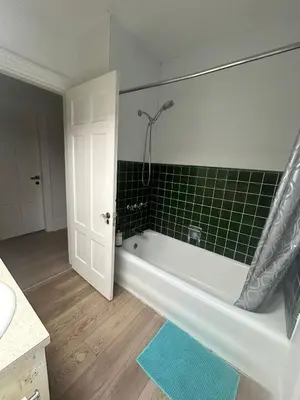 a bathroom with a tub and a green tiled wall at Vancouver Budget Rooms Near Beach & Transit - Fast WiFi & Free Parking in Vancouver