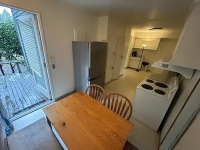 a small kitchen with a table and a refrigerator at Vancouver Budget Rooms Near Beach & Transit - Fast WiFi & Free Parking in Vancouver