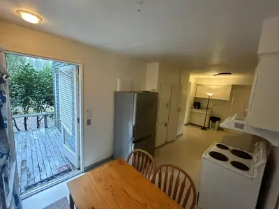 a kitchen with a refrigerator and a table with chairs at Budget Vancouver Rooms Near YVR - Free Parking, Fast WiFi in Vancouver