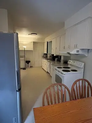a kitchen with white appliances and a table and chairs at Budget Vancouver Rooms Near YVR - Free Parking, Fast WiFi in Vancouver