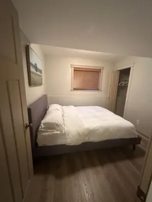 a bedroom with a bed with white sheets and a window at 2-Bedroom Private Suite near VIU in Nanaimo