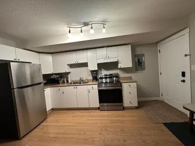 a kitchen with white cabinets and a stainless steel refrigerator at 2-Bedroom Private Suite near VIU in Nanaimo