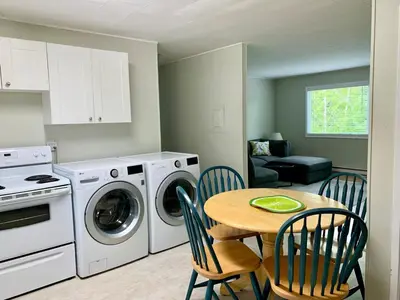 a kitchen with a table and a washer and dryer at Hidden JEM - Your Home Away From Home in Coal Harbour