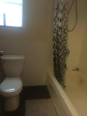 a bathroom with a toilet and a tub and a window at Quiet-comfy 3 bedroom house on a tree lined street in Kitsilano in Vancouver