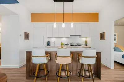a kitchen with white cabinets and a bar with stools at Spacious and elegant| 2 Kng Beds| Space for all in Calgary