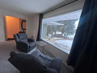 a living room with a couch and a chair and a large window at Cozy West Edmonton Home Near Jasper Park & shops in Edmonton