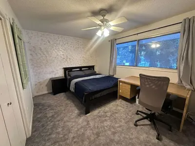 a bedroom with a bed and a desk and a window at Cozy West Edmonton Home Near Jasper Park & shops in Edmonton