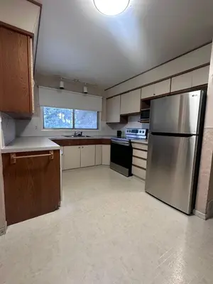 an empty kitchen with a stainless steel refrigerator at Cozy West Edmonton Home Near Jasper Park & shops in Edmonton