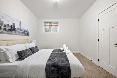 a white bedroom with a large bed and a window at Spacious Modern 3 Bedroom Basement Suite in Calgary