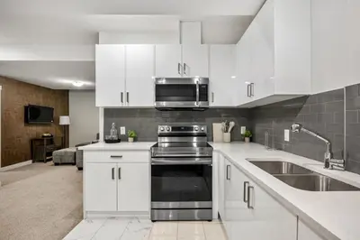 a kitchen with white cabinets and a sink and a microwave at Spacious Modern 3 Bedroom Basement Suite in Calgary