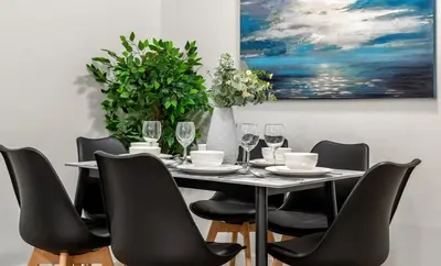 a dining room with a table with chairs and a painting at Spacious Modern 3 Bedroom Basement Suite in Calgary