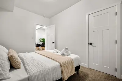 a white bedroom with a bed with a teddy bear on it at Spacious Modern 3 Bedroom Basement Suite in Calgary